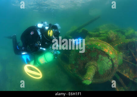 Diver with the metal detector searching for underwater treasure near to the wrack railway carriage, lake Baikal, Siberia, Russia Stock Photo