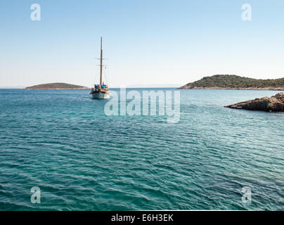 charter boat carrying day trippers passing between islands on the blue green waters of the turkish aegean coast. Stock Photo