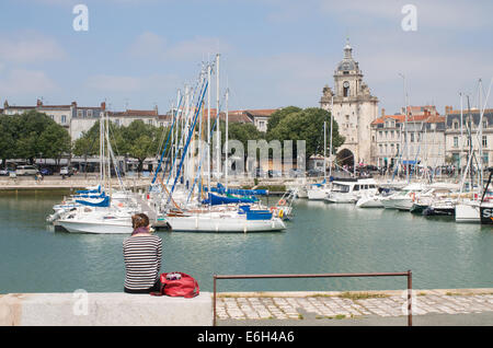 Young woman sitting on harbour wall La Rochelle, Charente-Maritime, France, Europe Stock Photo