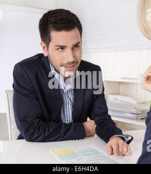 Adviser sitting in a meeting with a blank on the table explaining something his colleague. Stock Photo