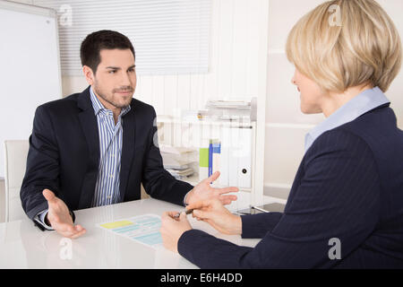 Job interview or meeting situation: business man and woman sitting at desk explaining something. Stock Photo