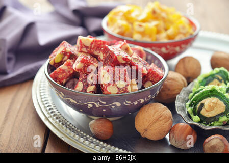 Turkish delight with nuts and sesame in ceramic bowl on wooden background Stock Photo