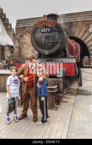 Engineer poses with children in front of the Hogsmeade Express train engine in The Wizarding World of Harry Potter Stock Photo