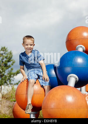 Six year old boy sits on the climbing frame Stock Photo