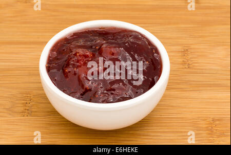 Small pot of strawberry Jam on a wooden board Stock Photo