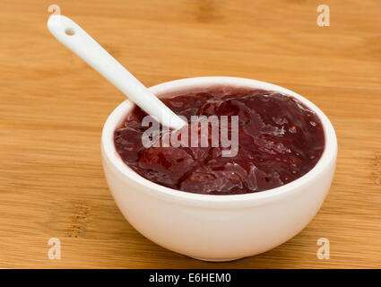 Small pot of strawberry Jam on a wooden board Stock Photo