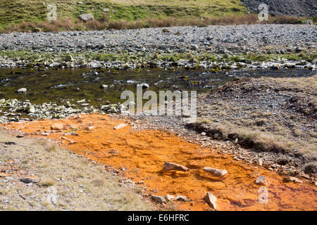 Polluted contaminated water flowing from stream from abandoned lead mine into river with clean water Cwmystwyth Mid Wales UK Stock Photo