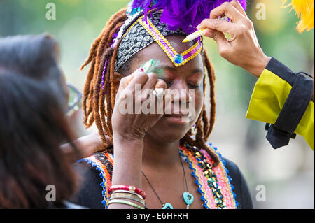 A woman with dreadlocks receives colorful face paint and vibrant accessories during the Carifest parade in Calgary Alberta Canada Stock Photo