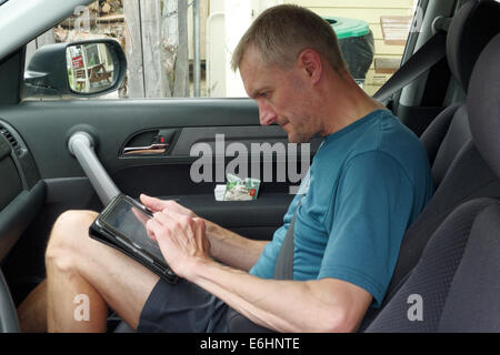 A man sat in a car using an ipad Stock Photo