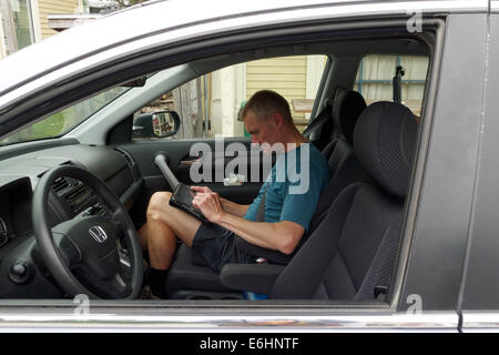A man sat in a car using an ipad Stock Photo