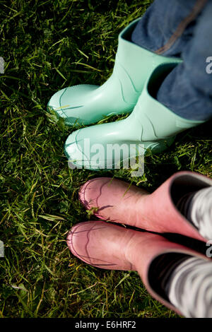 'Point of view' of children wearing wellington boots on grass. Stock Photo