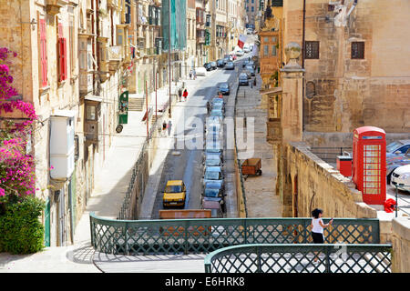 Typical one way residential street with parked cars in the capital city of Valletta Malta including British red phone box Stock Photo
