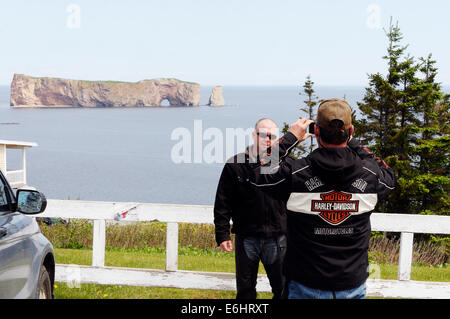 A biker taking pictures of his friend and of the Rocher Percé in Gaspesie, Quebec Stock Photo