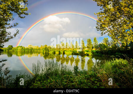 Bright rainbow reflected in a fishing lake Stock Photo