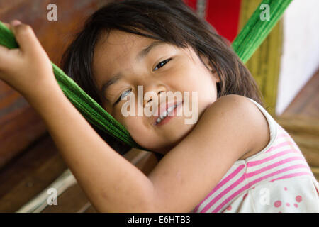 Smiling young Cambodian girl, playing with a hammock, in the city of Siem Reap, Cambodia, home to the ancient temples of Angkor Wat. Stock Photo