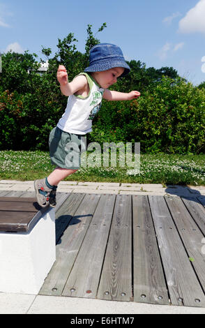 A two year old boy jumping from a bench Stock Photo