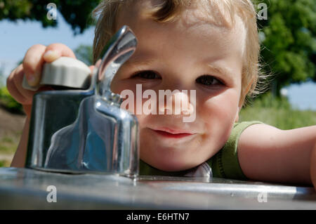 A young boy playing with a drinking water fountain Stock Photo