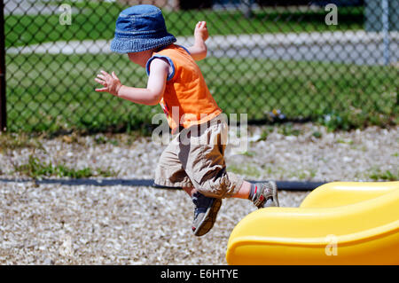 A two year old boy jumping from a slide Stock Photo