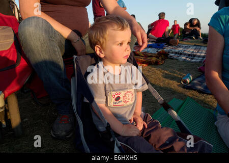 A two year old boy sat in a deck chair at a music festival, the Festival d'Été du Quebec