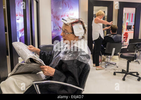 OLDER WOMAN IN HAIR SALON HAVING HAIR CUT AND STYLED BY 