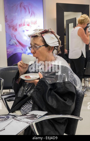 OLDER WOMAN IN HAIR SALON HAVING HAIR CUT AND STYLED BY 