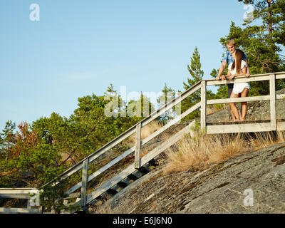 Young couple together on the fence, rocky and wooden environment Stock Photo