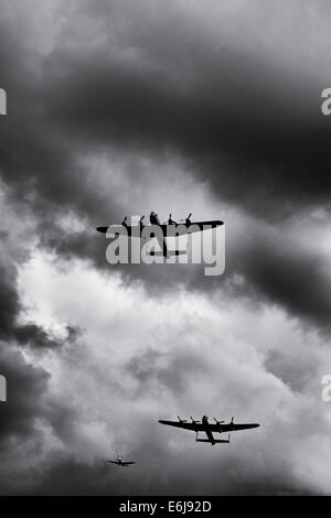 Lancaster bomber and spitfire planes fly past against stormy rainclouds at Military Odyssey show, Detling, Kent, England. Stock Photo