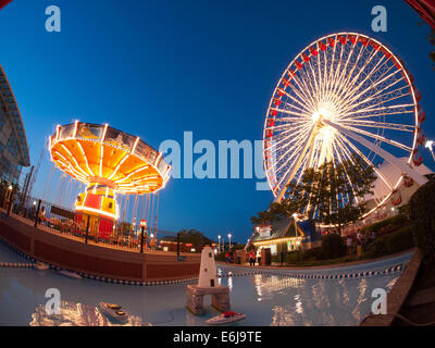 A night, fisheye view of the popular Wave Swinger and Ferris Wheel rides at Navy Pier in Chicago. Stock Photo