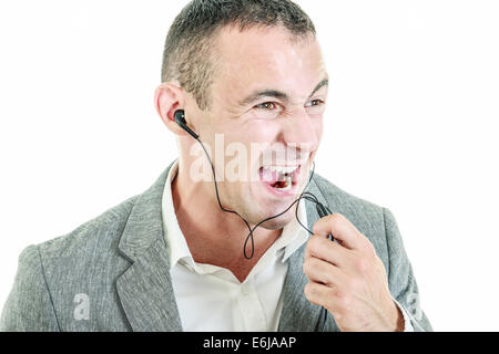 Man wearing earbuds talking on mobile phone shouting on phone microphone Stock Photo