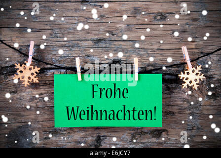 A Green Label with the German Words Frohe Weihnachten, which means Merry Christmas on it, Snowy Christmas Background Stock Photo