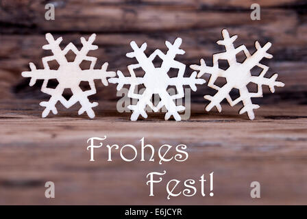 Three Snowflakes on Wood with the German Words Frohes Fest which means Merry Christmas Stock Photo