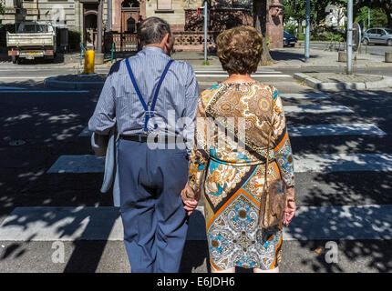 Back view of elderly couple holding hands while waiting to cross the street at pedestrian crossing Strasbourg Alsace France Europe Stock Photo