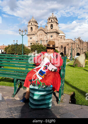 Quechua woman crocheting in plaza de Armas and the Iglesia de la Compañía de Jesus in the background - Cusco, Peru Stock Photo
