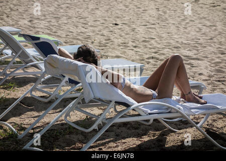 A tattooed Caucasian woman in a bikini enjoys relaxing on the beach of St. Croix, U.S. Virgin Islands. Stock Photo