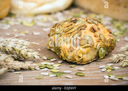 Freshly baked roll with pumpkin seeds on wooden table Stock Photo