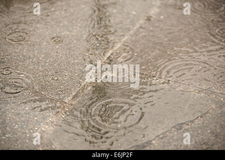 raindrops causing ripples patterns in puddle over flagstone pavement ...