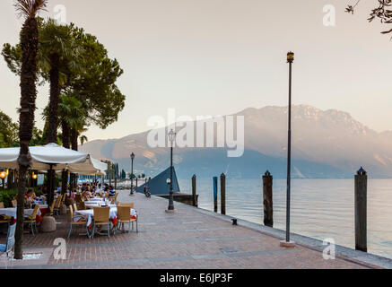Restaurant on the harbourfront at sunset in the old town, Riva del Garda, Lake Garda, Trento, Italy Stock Photo