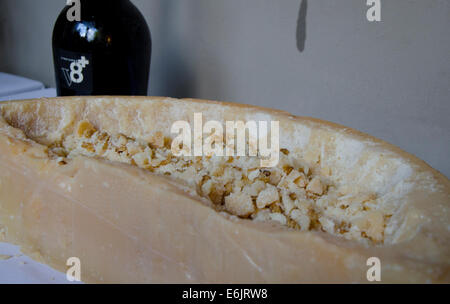 Hollowed out Parmesan, Parmigiana reggiano, wheel serving as a pot. Prosecco in the background. Italian cheese served. Italy. Stock Photo