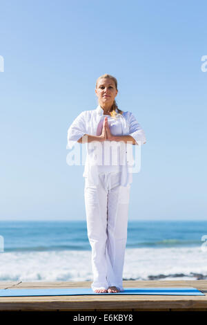 fit senior woman yoga on beach Stock Photo