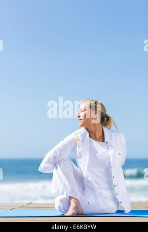 peaceful senior woman at the beach doing yoga Stock Photo