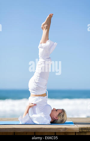 senior woman doing stretching exercise at the beach Stock Photo