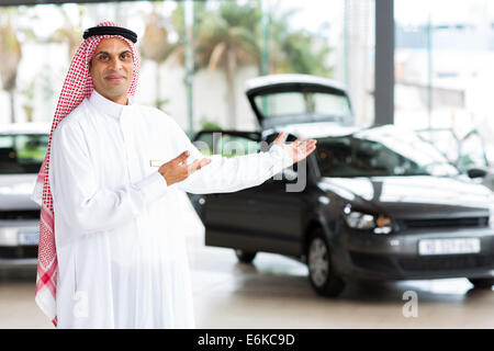 friendly Arabian car salesman doing welcoming gesture Stock Photo