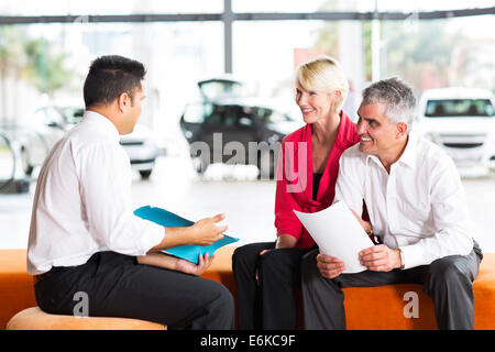 vehicle salesman explaining contract to senior couple before buying a car Stock Photo
