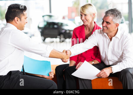 happy car salesman handshaking with senior buyer Stock Photo