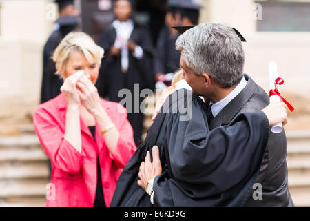 middle aged father hugging daughter at graduation ceremony Stock Photo