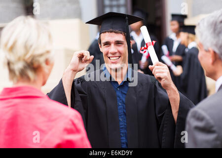 excited male graduate holding his diploma at graduation Stock Photo