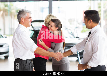 senior man buying car for his daughter handshaking with dealer after the sale Stock Photo