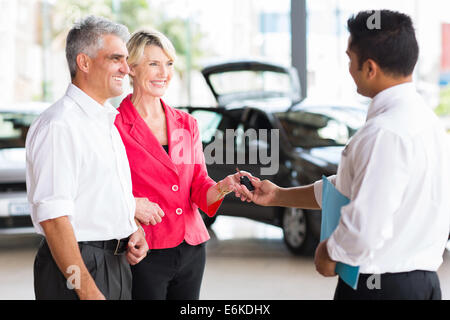 senior couple receiving car key after buying a new car Stock Photo
