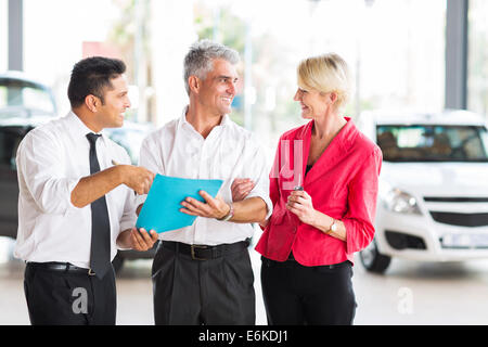 middle aged man talking to wife before buying a new car at dealership Stock Photo