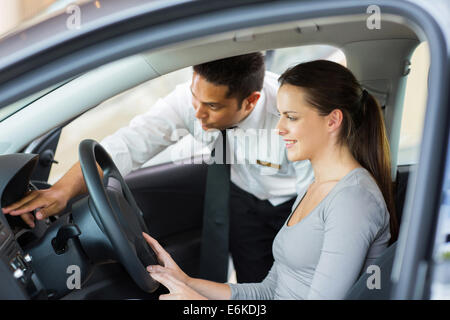 friendly salesman explaining car features to young female customer Stock Photo